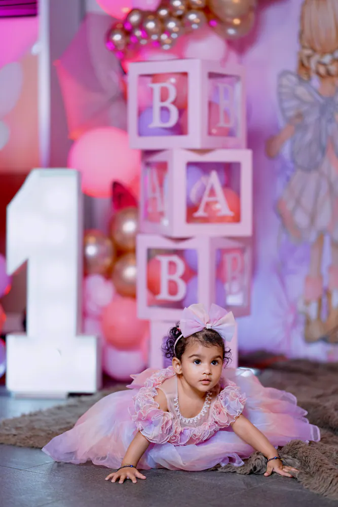 Baby girl in a lilac tutu with BABY letter blocks and balloons at her first birthday shoot