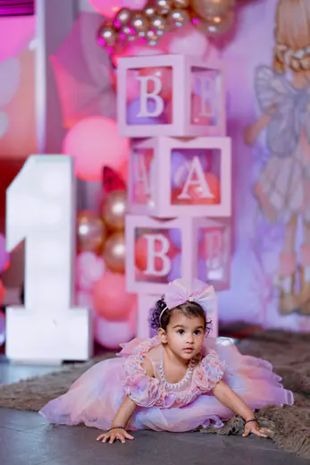 Baby girl in a lilac tutu with BABY letter blocks and balloons at her first birthday shoot