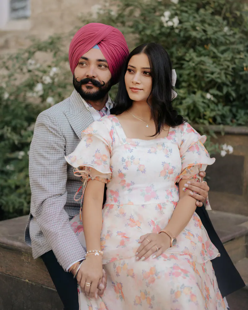 Couple seated together in a garden, the bride in a floral dress