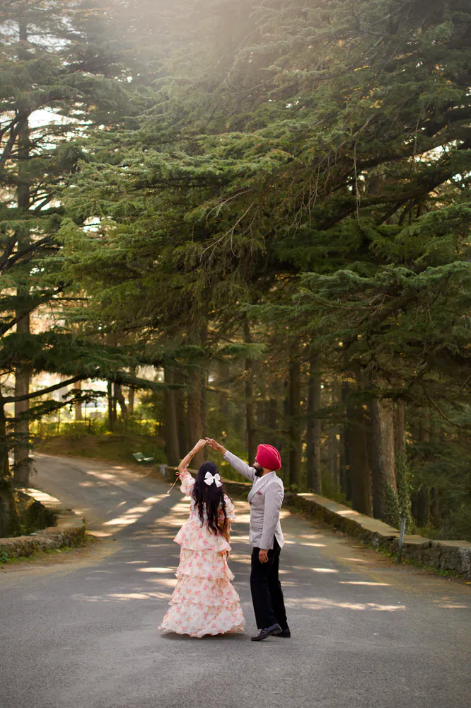 Couple dancing on a road between tall pine trees