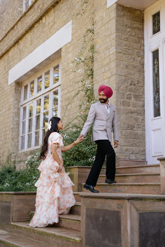 Groom leading his bride up the stone steps of a hill-station cottage