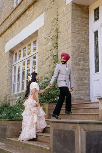Groom leading his bride up the stone steps of a hill-station cottage