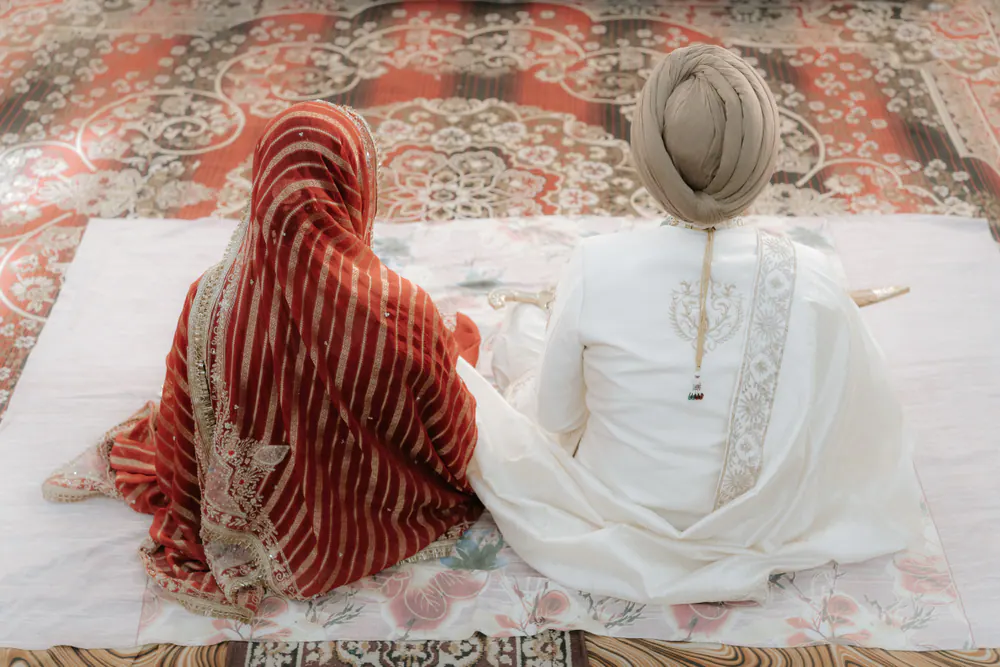 Sikh bride and groom seated together during the Anand Karaj ceremony