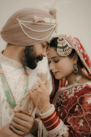 Sikh groom and bride touching foreheads in an intimate wedding portrait
